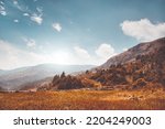 Autumn mountain valley against blue cloudy sky. Bright orange grass and mountain range in Nepal Himalayas. Amazing natural summer scenery. Stunning wild nature. Creative image for design