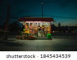 Roadside flower shop during night time. Lonely flower shop late at night, with flowers visible blooming under neon lights.
