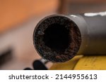 Small photo of Residue or thick layer of soot after a poor combustion in a fireplace, layered on the inner part of a chimney pipe or smokestack. Dangerous situation for fire, fire hazard.