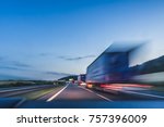 Background photograph of a highway, trucks on a highway, motion blur, light trails. Evening or night shot of trucks doing transportation and logistics on a highway.