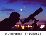 Girl looking at the stars with telescope beside her and de-focused city lights. My astronomy work.