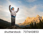 a child conquers the summit, loose his proud arms, in the background the Alps