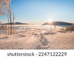 Footprints of the first climber to reach the summit during sunrise in Beskydy mountains, Czech republic. Breathtaking winter scenery with a view of passing clouds and sun. Hiking lifestyle.