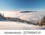Mountainsides of the Beskydy region in the Czech Republic are sinking into a thick white inversion rising from the cities. Winter fairytale scenery in central Europe.