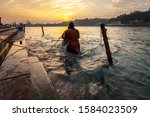 Small photo of Two woman taking a dip in river Ganga at sunset. Dipping is a ritual infused with religious beliefs. The water of this holy river is meant to absolve people of their sins