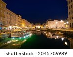 Canal Grande di Trieste at night with beautiful buildigs and refletion on the water .