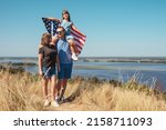 Happy family with american flag enjoying nature on a sunny summer day. Free lifestyle. Family entrance
