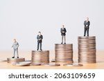Small photo of Different miniature businessman standing on different height coins stacking , Inequality income and salary in each position in company concept.