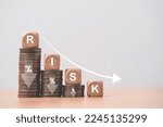Risk wording on decreasing coins stacking with down arrow for financial banking risk analysis and management ,Low risk low return concept.