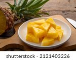 Ripe pineapple slice on white plate on a wooden table