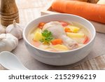 Clear chicken soup with potatoes carrot and onion in white bowl.Asian style food
