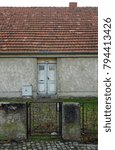 Small photo of Berlin, Germany - 11 24 2016: Close-up of an ancient, unmodernized House with Door, Garden, Fence and red Roof