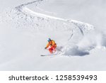 one freeride skier skiing downhill trough deep fresh powder