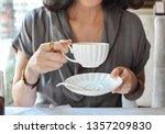 
Elegance female holding white cup and plate in English etiquette, crop not have face beautiful woman sitting relax with high tea time at restaurant, for happy with afternoon tea concept  