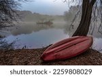 Small photo of An overturned boat on the shore of a misty forest lake. Boat at lake tree in fog. Boat on lakeshore in fog. Foggy lakeview with overturned boat