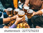 Group of friends drinking and toasting glass of beer at brewery pub restaurant- Happy multiracial people enjoying happy hour with pint sitting at bar table- Youth Food and beverage lifestyle concept

