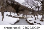 Small photo of In the depths of winter, the once-flowing stream in Shirakawa village stands still, encased in a layer of ice. The frozen waterway winds through the village, mirroring the crystalline world around it.