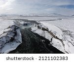 Drone shot of Godafoss waterfall, Iceland, taken from a high angle. Aerial view of the powerful cascade, river and snow covered rocks. Late autumn, early winter scene.