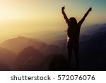 silhouette woman rising hands on mountain in morning with vintage light