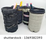 Small photo of Handmade craft recycle bottle and jeans become pencil stationary case desk. Tube box shape with top hole. Decoration with sand, button and bordir embroidery. Work process cut sewn taped glued dry.