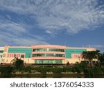 Small photo of Surabaya, Indonesia - April 21 2019: View of the back of JMP Grocery Mall Market Building with clear blue sky clouds and river background with trees around. Nearby with Red Bridge Historical Duct area