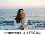 Portrait of a happy young woman on a background of beautiful sea. The girl looks at the magical sea. Freedom and happiness