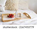 Still life details in home interior of living room. Tray, cup coffee, strawberries and card on a bed. Cozy home