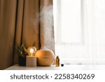 Aromatherapy concept. Aroma oil diffuser on the table against the window. Air freshener. Ultrasonic aroma diffuser for home