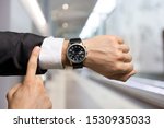 Businessman pointing at hand watch on grey