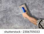 worker hand with steal trowel plastering cement on wall