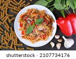 Plate of Delectable Whole Wheat Fusilli Pasta in Tomato Sauce with Its Ingredients Scattered Around
