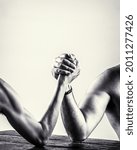 Small photo of Arm wrestling. Heavily muscled bearded man arm wrestling a puny weak man. Black and white.