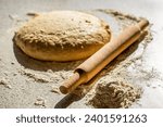 Small photo of Wooden rolling pin with freshly prepared dough, flour shaker. Fresh raw dough and rolling. Raw dough for pizza or bread baking. Rolled doughs with rolling pin on table covered baking flour.