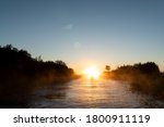 Sunrise sky background. Gold sunrise sky with sky clouds over the lake with fog.Crystal clear water texture. Small waves with water reflection