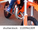 the child is sitting on a small orange sports pitbike, the moto sport theme
