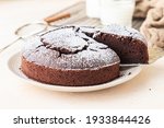 Chocolate sponge flourless cake with sugar powder, light concrete background. Brownie cake. Toned image. Selective focus