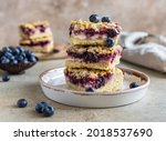 Small photo of Crumble cheesecake bars with blueberry filling and fresh blueberries, concrete background. Bar slices with cheesecake, blueberry and streusel. Selective focus.