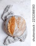 Small photo of Rustic Bread with on a napkin on a white table. Scoring an ears and wheat pattern. Cooking of healthy bread from alternative flours. Vegan bread. High quality photo