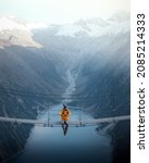 Small photo of Man in yellow jacket sitting on a suspension bridge over a lake in Olpererhutte, Austria