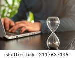 Hourglass with time running out in an office as a symbol of time pressure at work
