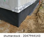 Black plastic drainage membrane fixed on the foundation of house under construction
