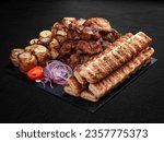 Small photo of A set of grilled meat. Lula kebab, pork gammon, veal steak and baked potatoes. Isolated on a dark background