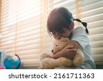 Small photo of Close up lonely little girl hugging toy, sitting at home alone, upset unhappy child waiting for parents, thinking about problems, bad relationship in family, psychological trauma