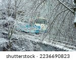 Magic fairy winter outdoor cityscape after snowfall: blue funicular in Kyiv (Kiev, Ukraine) going down the hill, snow-covered frosted branches of trees and railroads around, urban public transport 
