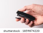 hand holding a black stapler on a white background. Craft, paper, office concept.