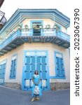 Small photo of PANO LEFKARA, CYPRUS - AUGUST 5, 2021: Russian tourist woman in Pano Lefkara village, Cyprus. Architectural fashion. Retro look with collar, dress. Street style, trendy outfit. Pano Lefkara landmark