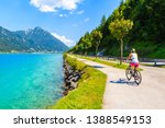 Young woman tourist riding bike along Achensee lake on sunny summer day, Pertisau, Tirol, Austria