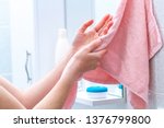 Person using towel for wiping hands dry after washing in bathroom at home. Hygiene and hand care 