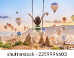 Dreaming woman swinging in Kapadokya. Flying hot air balloons in Anatolia. Happy moment life in beautiful destination in Goreme, Nevsehir 