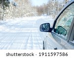 Snowy road. Side of a car with a mirror. Snowy forest in the afternoon 